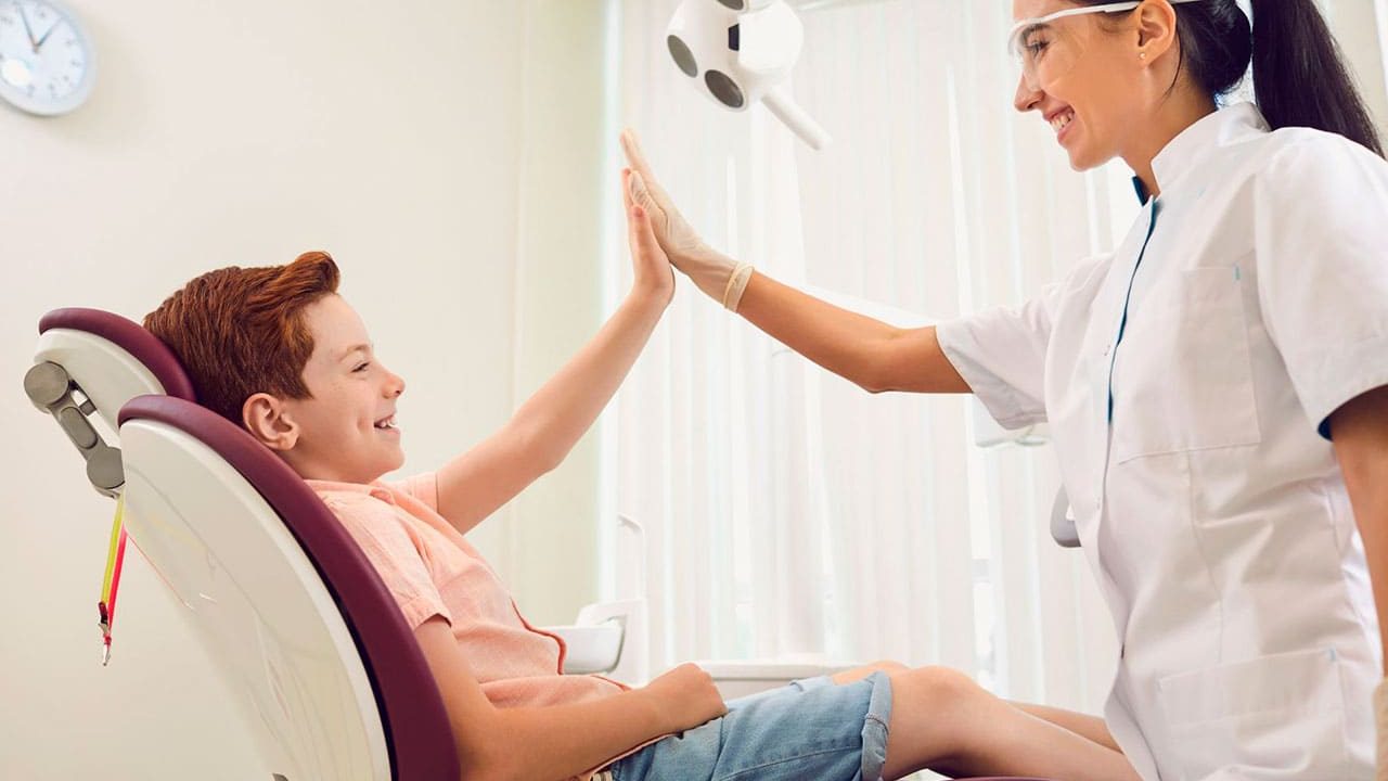 um dentista sorridente realizando um exame bucal em um paciente